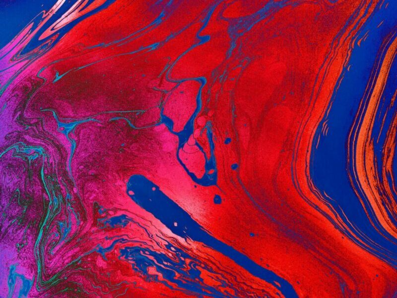Dynamic and colorful abstract painting with bold fluid patterns in red, blue, and purple hues.